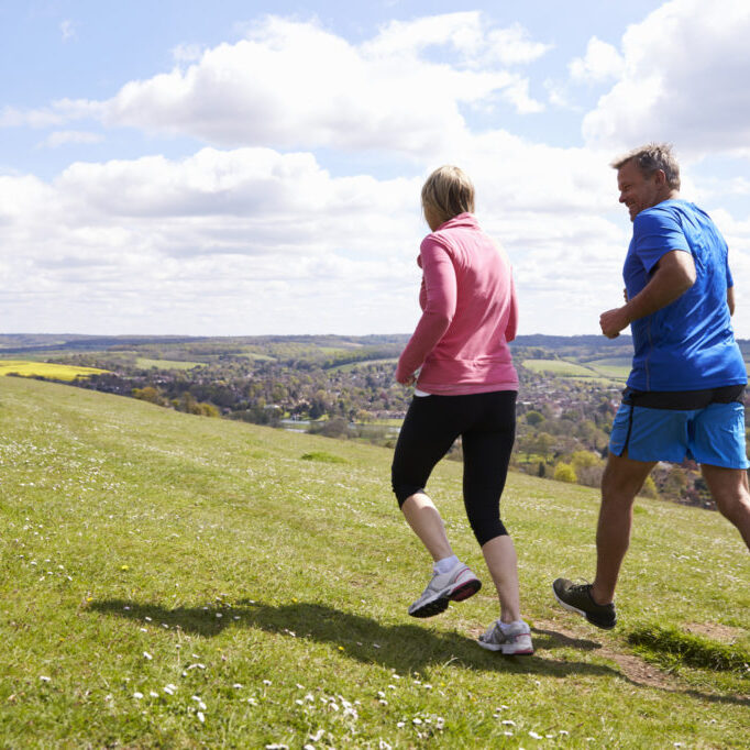 Rear View Of Mature Couple Jogging In Countryside